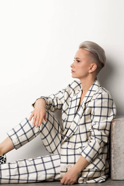 Elegant ant charismatic short blond haired with natural makeup businesswomen wearing oversized linen suit with blue stripes posing isolated in studi - Photo, Image