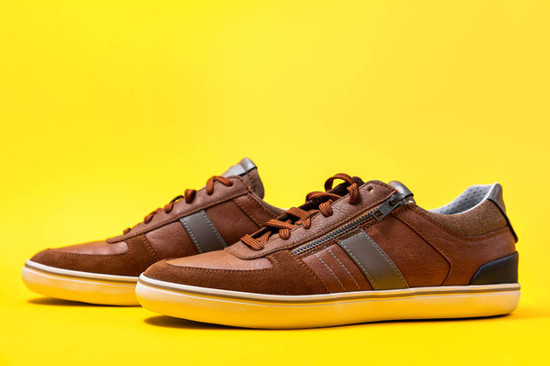Pair of male's new sneakers made of brown leather on a yellow background. Copy space. - Photo, Image