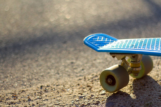 Defocus zavřít modrý skateboard na ráno v parku. Vedoucí skateboardu a kola na silnici ve veřejném parku. Sportovní koncept. Rozmazaný zadek. Moderní moderní pozadí. Rozostřeno. - Fotografie, Obrázek