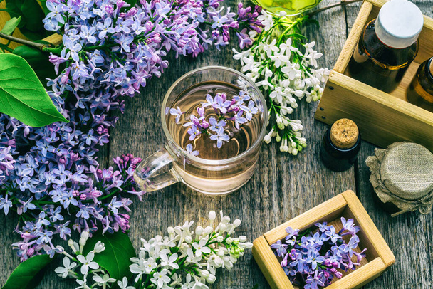 Eteerinen öljy ja kuppi teetä valmistettu lila kukkia  - Valokuva, kuva