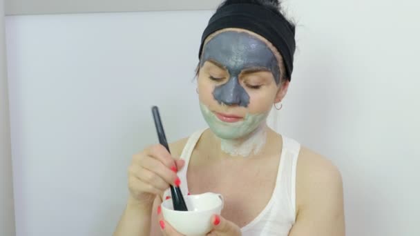 顔の粘土マスクを混合ブラシで女性。美容トリートメントのコンセプト - 映像、動画