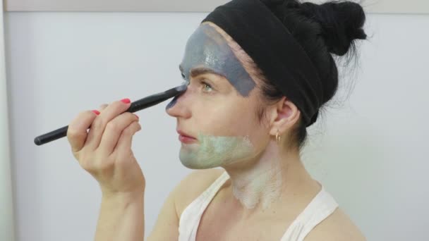 Γυναίκα που εφαρμόζει μάσκα προσώπου. Έννοια φροντίδας του δέρματος προσώπου - Πλάνα, βίντεο