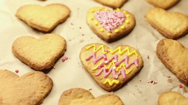 mujer decora galletas con corazones de pastelería, primer plano, proceso de preparación de postres - Metraje, vídeo