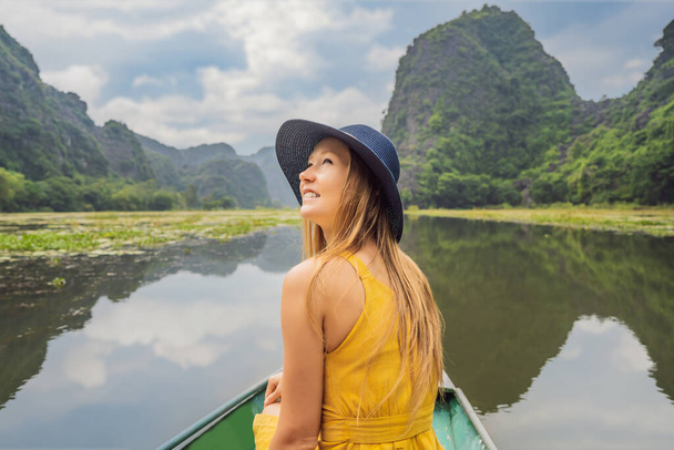 Kobieta turysta w łodzi na jeziorze Tam Coc, Ninh Binh, Viet nam. Jest wpisany na Listę Światowego Dziedzictwa UNESCO, słynie z wycieczek po jaskiniach łodzi. Zatoka Halong na lądzie Wietnamu. Wietnam ponownie otwiera granice po - Zdjęcie, obraz