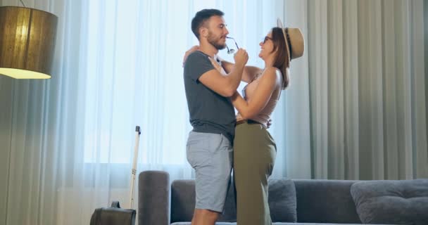 Ευτυχισμένος άνδρας και γυναίκα αγκαλιά κοντά σε μεγάλο παράθυρο στο δωμάτιο του ξενοδοχείου - Πλάνα, βίντεο