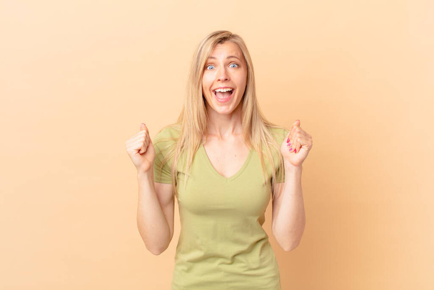 young blonde woman feeling shocked,laughing and celebrating success - Foto, Bild