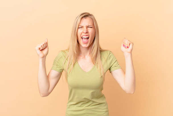 young blonde woman shouting aggressively with an angry expression - Foto, immagini