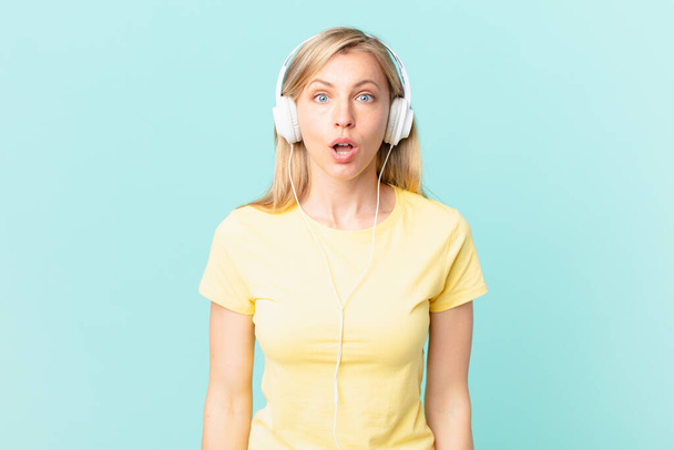 young blonde woman looking very shocked or surprised and listening music. - Fotografie, Obrázek