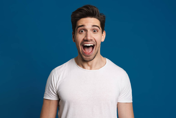 Excited unshaven guy expressing surprise on camera isolated over blue background - Foto, Bild