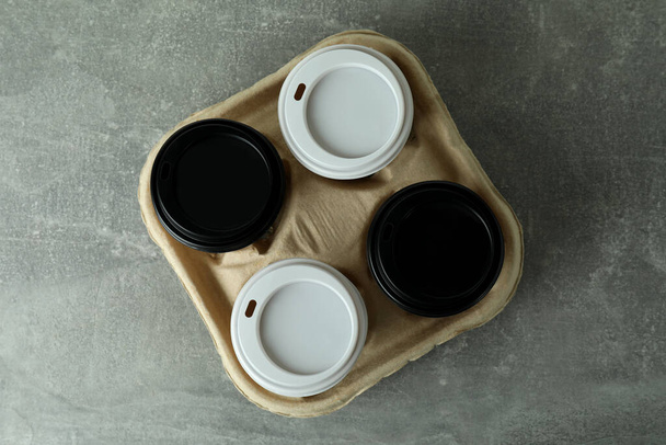 Cup holder with coffee cups on gray textured background - Foto, afbeelding