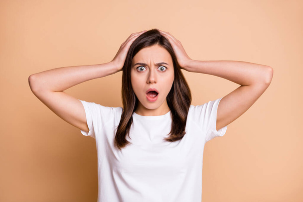 Photo portrait of amazed shocked frustrated stressed girl keeping head with hands isolated pastel beige color background - Φωτογραφία, εικόνα