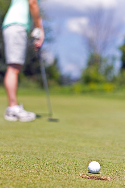 Woman sinking a putt on a golf green - selective focus - Photo, image