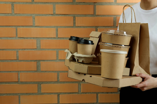 Woman hold delivery containers for takeaway food on brick wall background - Foto, Imagem
