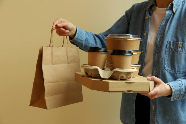 Woman hold delivery containers for takeaway food on beige background - Photo, Image