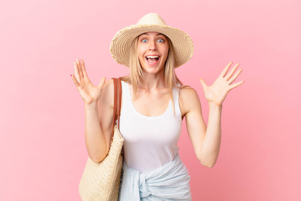 young blonde woman feeling happy and astonished at something unbelievable. summer concept - Foto, Imagem