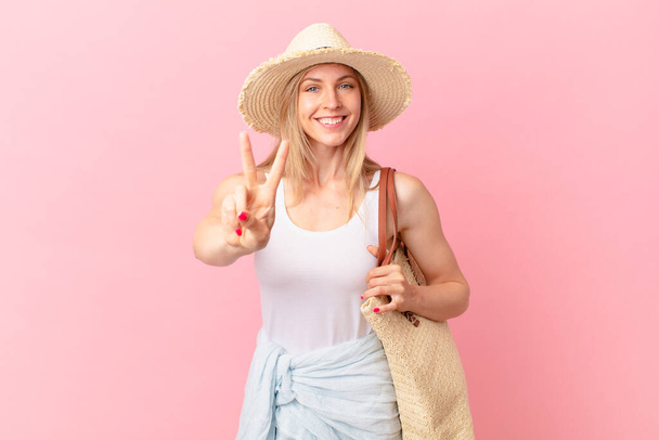 young blonde woman smiling and looking friendly, showing number two. summer concept - Foto, Bild