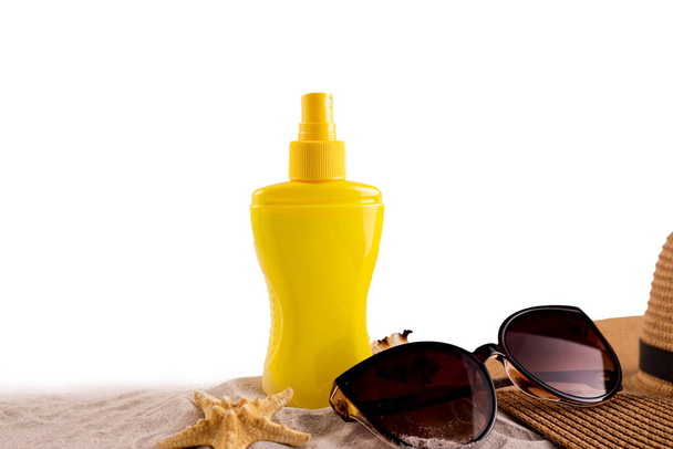 Botella de spray protector solar y zapatos de playa sombrero de paja de verano y gafas de sol contra el espacio de copia blanca. Concepto de bandera de vacaciones de verano. - Foto, imagen