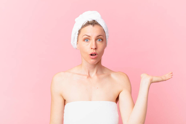 young blonde woman looking surprised and shocked, with jaw dropped holding an object and after shower - Foto, Imagem