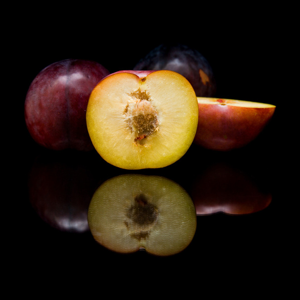 Ripe red and purple plum fruits; isolated on black background with reflection - Фото, изображение