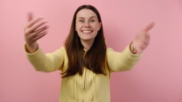 Positive attractive happy caucasian woman calling with hands, wanting to hug, glad to see, congratulating, posing isolated over pink color background. Come here into my hugs. People emotion concept - Video, Çekim