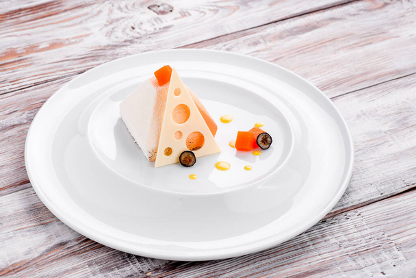 Bela sobremesa branca na forma de uma pirâmide em uma placa branca em um fundo de madeira leve. Espaço para texto - Foto, Imagem