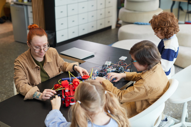 Portrait en grand angle d'une enseignante aidant des enfants à construire un robot en classe d'ingénierie à l'école, espace de copie - Photo, image