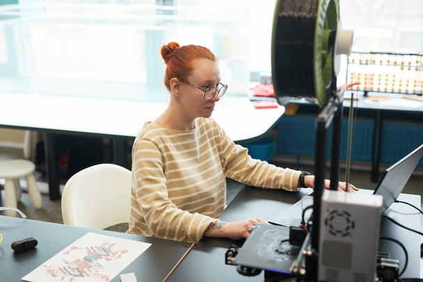 Magas szögű portré fiatal vörös hajú nő segítségével 3D nyomtató során mérnöki óra a főiskolán, másolás tér - Fotó, kép