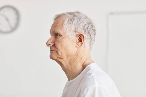 Retrato de visão lateral do homem idoso no hospital com foco em tubos de suporte de oxigênio, espaço de cópia - Foto, Imagem