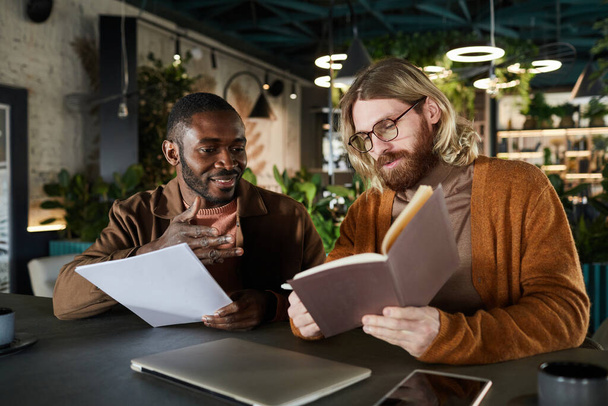 Πορτρέτο δύο σύγχρονων ανδρών που συνεργάζονται σε έργο κατά τη διάρκεια επαγγελματικής συνάντησης στο πράσινο γραφείο ή καφέ εσωτερικό, αντιγραφή χώρου - Φωτογραφία, εικόνα