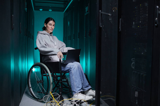 Sunucu odasında laptop kullanırken kameraya bakan engelli kadının tam boy portresi, erişilebilir iş konsepti, kopyalama alanı - Fotoğraf, Görsel