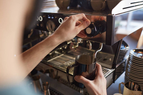 Close up of unrecognizable barista operating coffee machine while making fresh coffee in cafe or coffee shop, copy space - Photo, Image