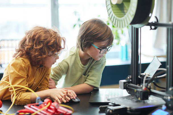 Retrato de dois meninos usando impressora 3D durante a aula de engenharia e robótica na escola, espaço de cópia - Foto, Imagem