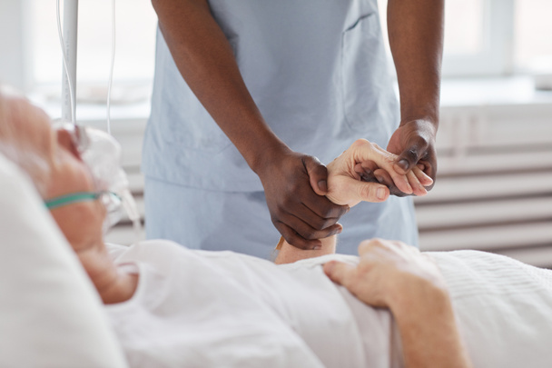 Κοντινό πλάνο της Αφροαμερικανής νοσοκόμας που κρατάει το χέρι του πρεσβύτερου στο νοσοκομείο και τον παρηγορεί, αντιγράφει χώρο. - Φωτογραφία, εικόνα