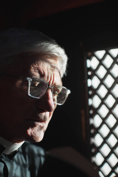Close-up de padre sênior em óculos sentados em confessionário - Foto, Imagem