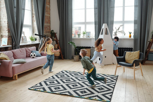 Gruppe von Kindern rennt durch den Raum und spielt gemeinsam im Raum - Foto, Bild