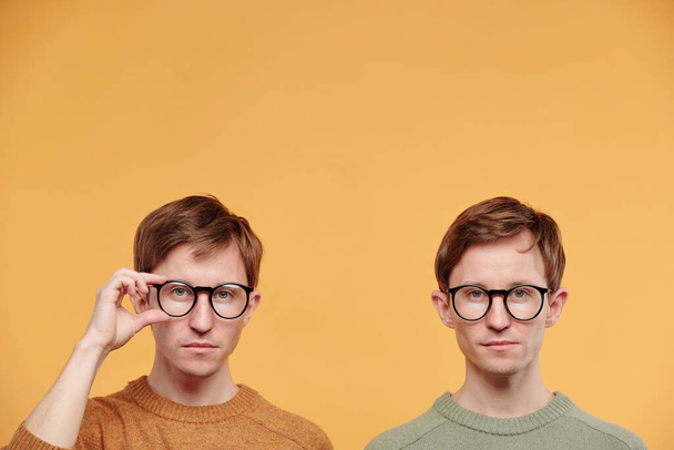 Retrato de preadolescentes inteligentes con propósito serio en gafas posando sobre fondo naranja - Foto, imagen