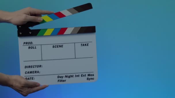 Movie Clapperboard. Man hand hold and move up film slate in to the frame and clap it and move down out of the frame. black and white movie slate clapperboard. colorful background. Video production.  - Footage, Video