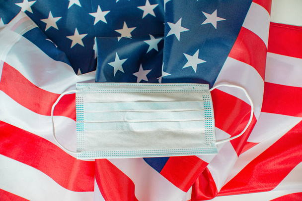 Medical mask on background with American flag. 4th of July Independence Day USA safety. Memorial day. Memorial Day concept. Federal holiday in the United States - Zdjęcie, obraz