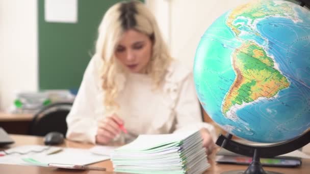 Δάσκαλος Γεωγραφίας ελέγχει τους μαθητές σημειωματάρια στην τάξη. Εκπαιδευτικός στην εργασία - Πλάνα, βίντεο