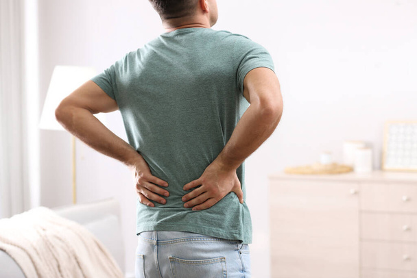 Man suffering from back pain at home. Bad posture problem - Photo, image