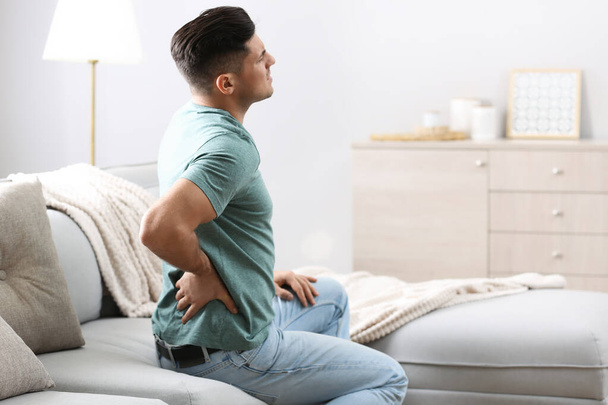 Man suffering from back pain at home. Bad posture problem - Φωτογραφία, εικόνα