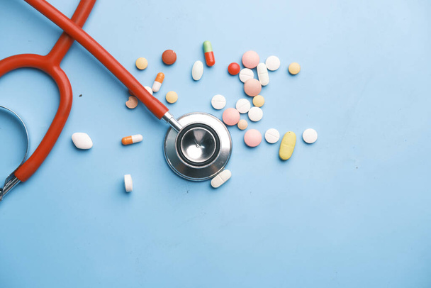  kleurrijke medische pillen en stethoscoop op blauwe achtergrond  - Foto, afbeelding