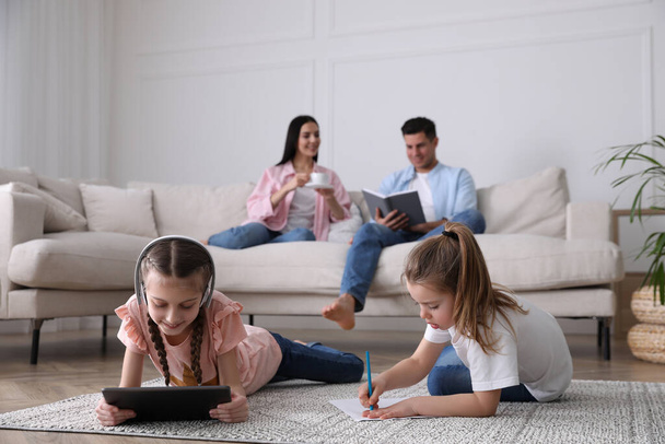 Family in living room with comfortable sofa, focus on children - Foto, afbeelding