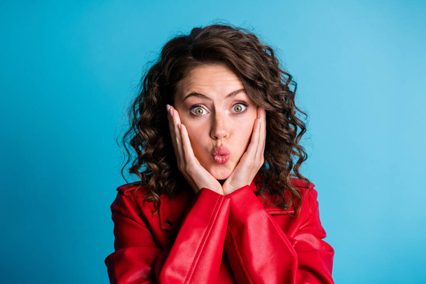 Portrait of optimistic girl hands face blow kiss wear red jacket isolated on blue color background - Фото, зображення