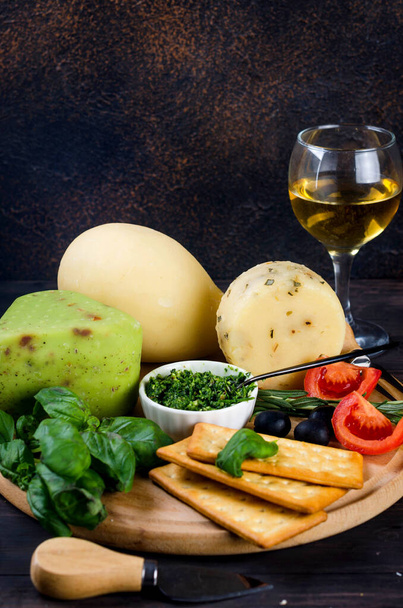 homemade cheese head with pesto basil on old dark wooden board and glass of wine on table. Fresh dairy product, healthy organic food. Delicious appetizer. - Foto, Bild