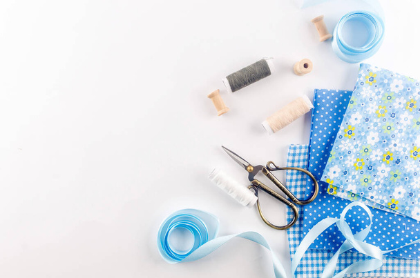 Set of blue sewing thread fabrics,  buttons and accessories on a white background. Flat lay composition with other sewing stuff. - Foto, afbeelding