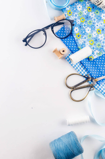 Set of blue sewing thread fabrics,  buttons and accessories on a white background. Flat lay composition with other sewing stuff. - 写真・画像