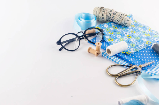 Set of blue sewing thread fabrics,  buttons and accessories on a white background. Flat lay composition with other sewing stuff. - Fotó, kép
