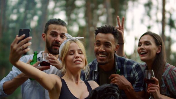 Szczęśliwi ludzie robiący grupowe zdjęcia w lesie. Wesoły przyjaciele pozowanie aparat - Zdjęcie, obraz