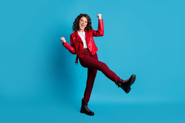 Full size photo of hooray cool girl wear red jacket trousers boots isolated on blue color background - Фото, изображение